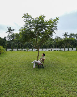 Man relaxing on bench against sky