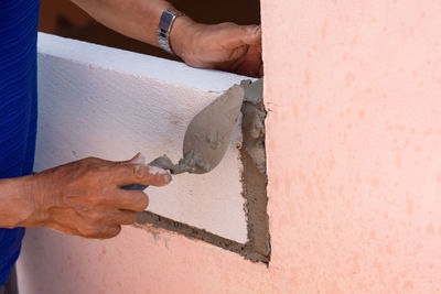 Midsection of man working on wood against wall