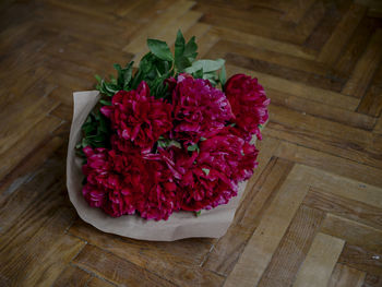 High angle view of red peonie on the hard wood floor