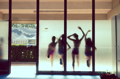 Rear view of girls in swimwear seen through glass partition