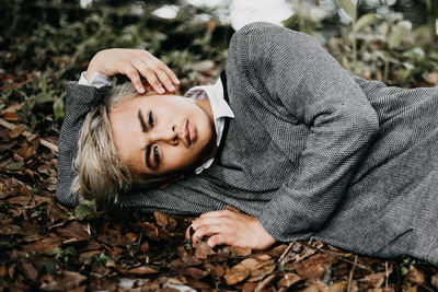 Portrait of young man lying on dry leaves covered field