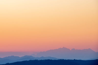 Scenic view of silhouette mountains against orange sky