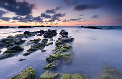 Scenic view of sea against dramatic sky during sunset