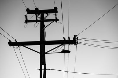 Low angle view of silhouette electricity pylon against sky