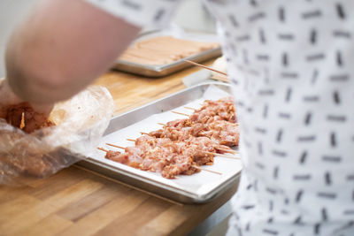 Mid section of man by meat in plate on table