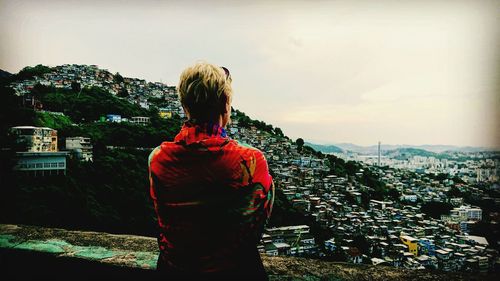 Rear view of woman standing by buildings against sky