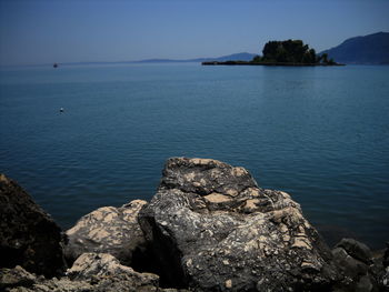 Rock formation in sea against clear sky