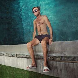 Full length of shirtless young man in swimming pool