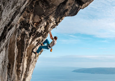 Full length of young man on rock against sky