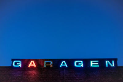 Low angle view of illuminated text against clear blue sky