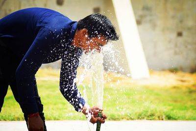 Man spraying water on face in park