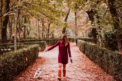 Smiling woman walking with dog on footpath