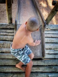 Full length of shirtless boy playing on wood