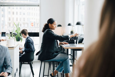 Side view of businesswoman working on laptop while sitting at desk in office cafe