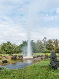 View of fountain on landscape against cloudy sky
