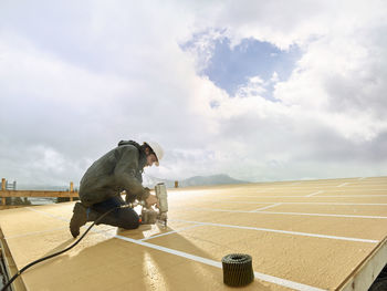 Carpenter using nail tool on wooden rooftop at construction site