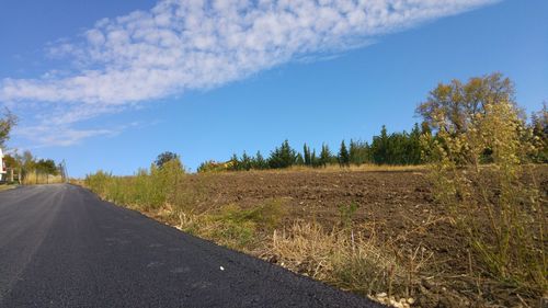 Road amidst field against blue sky