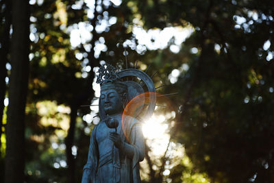 Low angle view of statue against forest