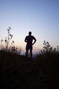 Rear view of silhouette man standing on field against sky