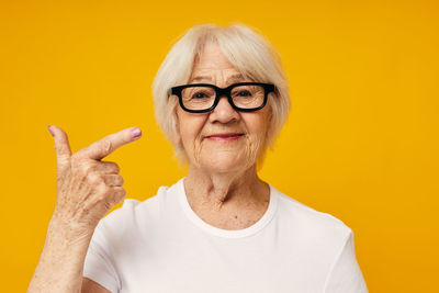 Portrait of young woman against yellow background