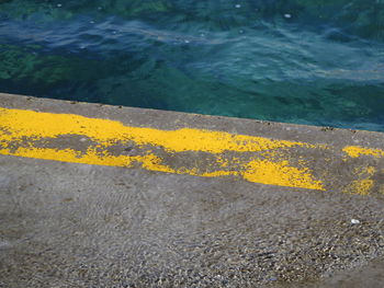 High angle view of yellow road by sea