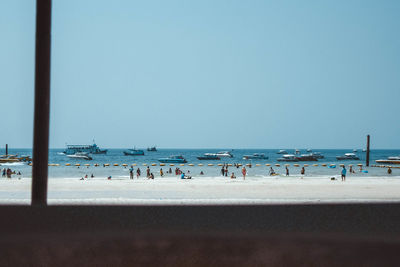 People on beach against clear blue sky