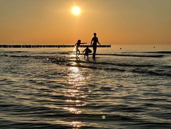 Silhouette woman walking on beach against sky during sunset