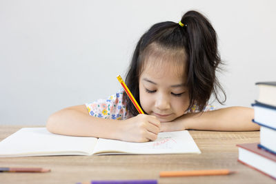 Girl drawing on book at table