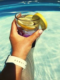 Midsection of man drinking glass against water