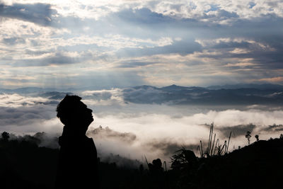 Silhouette people standing on mountain against sky during sunset