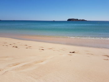 Scenic view of beach against clear blue sky