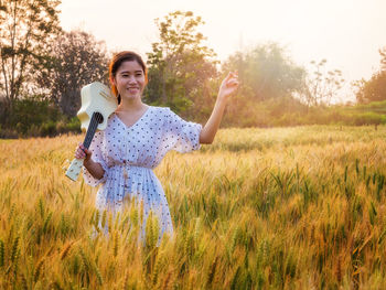 Portrait of young woman standing on field against sky