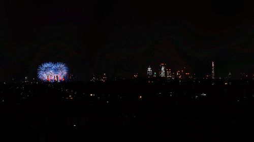 Firework display over illuminated buildings in city at night