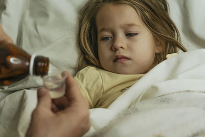 Female hands pour medicine for sick little girl