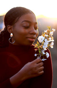 Portrait of a smiling young woman holding red flowering plant