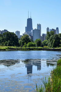 Modern buildings by lake in city against sky