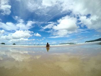 Rear view of man on beach against sky