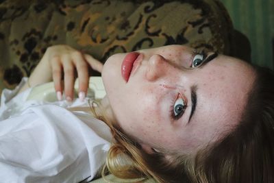 Close-up portrait of woman lying on bed at home