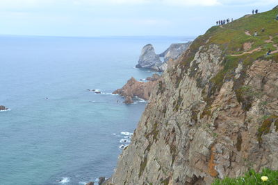 Scenic view of sea by cliff against sky