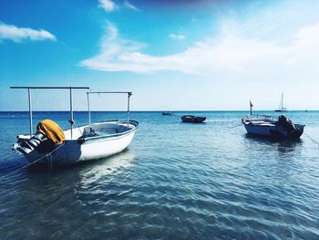 Sailboats moored on sea against sky