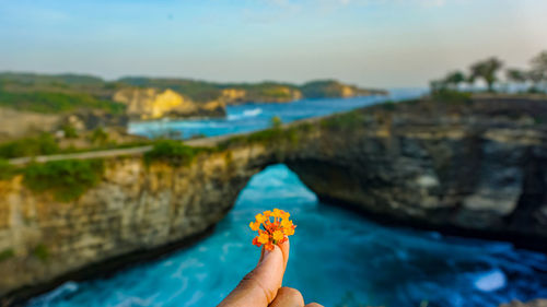 Low section of person on rock by sea against sky