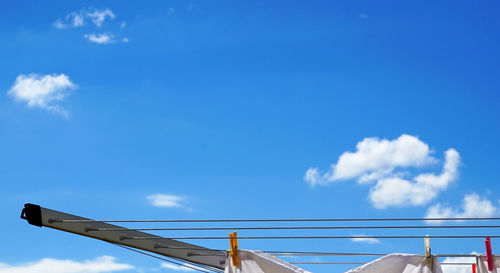 Fabric attached to clothespins on clotheslines against blue sky