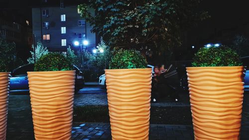 Multi colored umbrellas by illuminated street against buildings at night