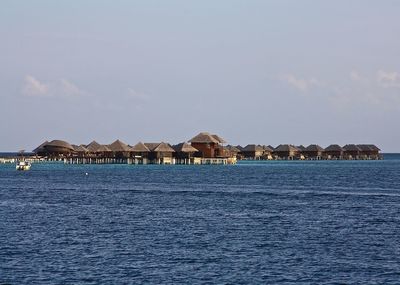 Stilt houses over sea against sky