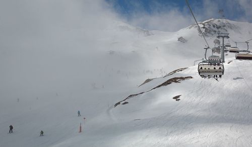 Ski lift over snowcapped mountains against sky