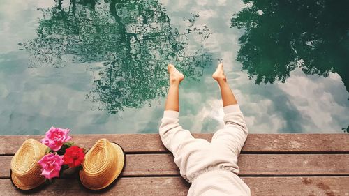 Low section of woman relaxing in swimming pool against sky