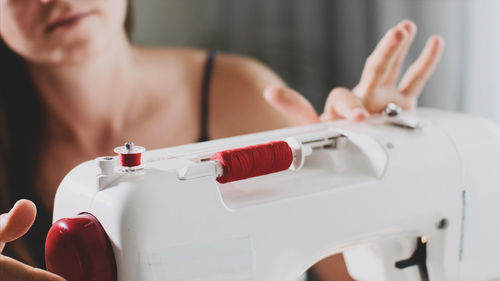 Midsection of woman using sewing machine