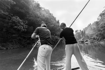 Rear view of man rowing raft in river