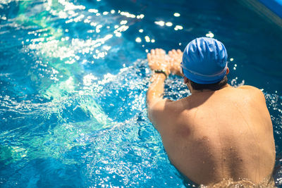 Rear view of man swimming in pool