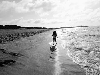 Rear view of people on beach against sky